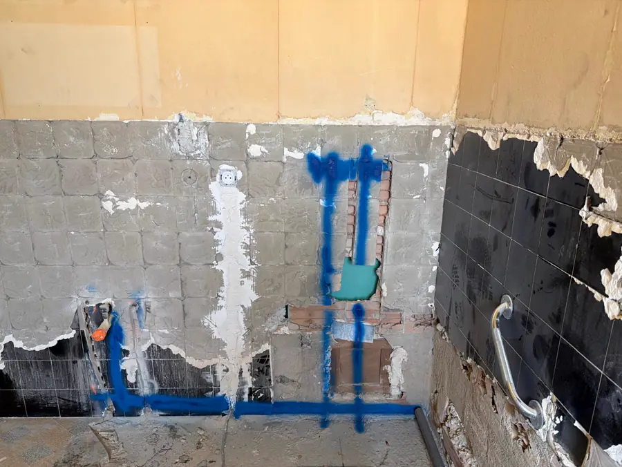 Tracé bleu du futur réseau d'eau et d'évacuation repéré sur le mur avant les saignées